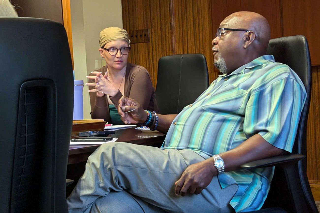 Dr. Cara Poland and Tommy Stallworth talking to each other. They are both sitting at a table