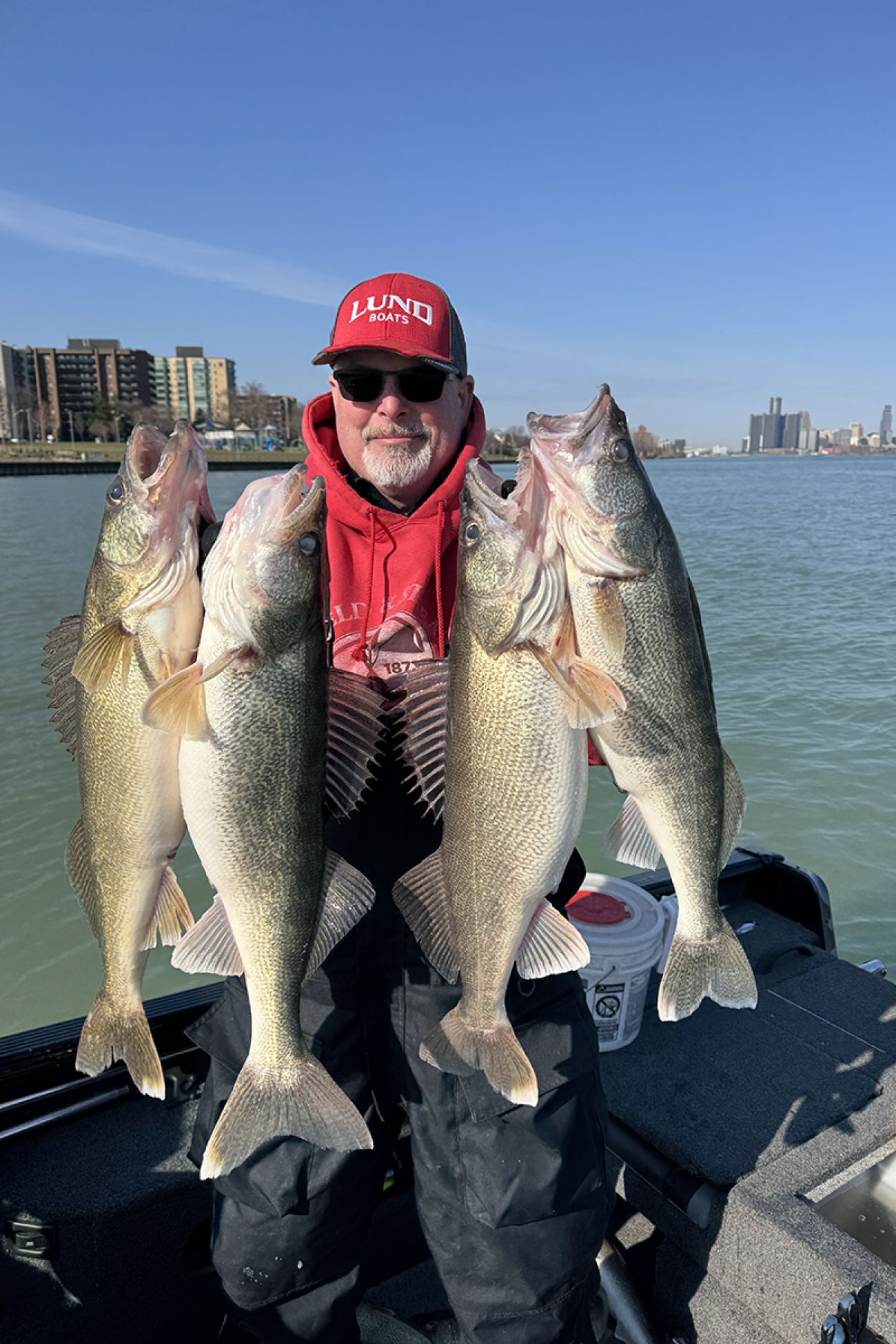 John “Jay” Addy IV holds up fish. He's wearing a red sweatshirt. 