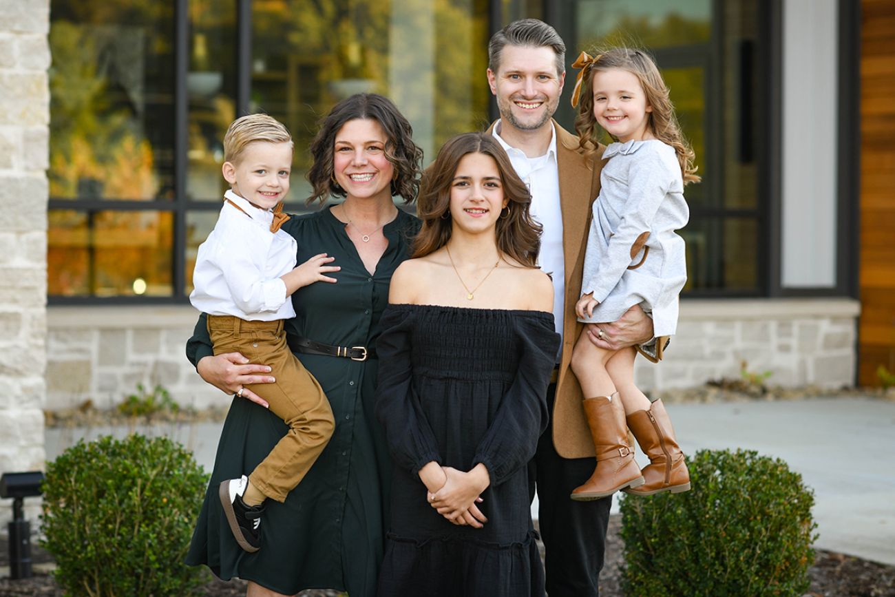 The Myers family on front of a building. There are three children in the family.