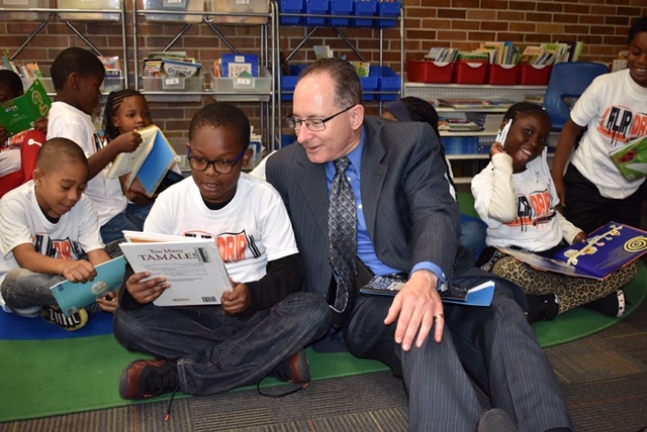 Michael Rice sits on the floor with children. 