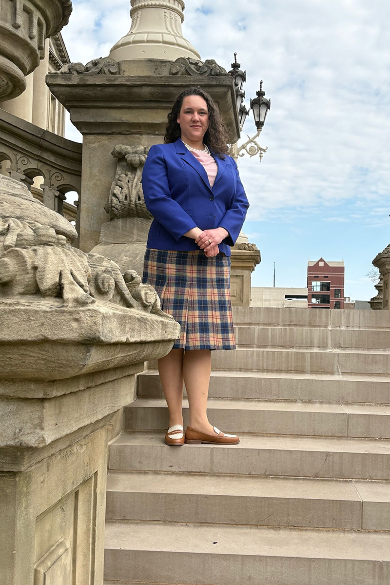 Leslie Desmond stands on steps in front of a building. 