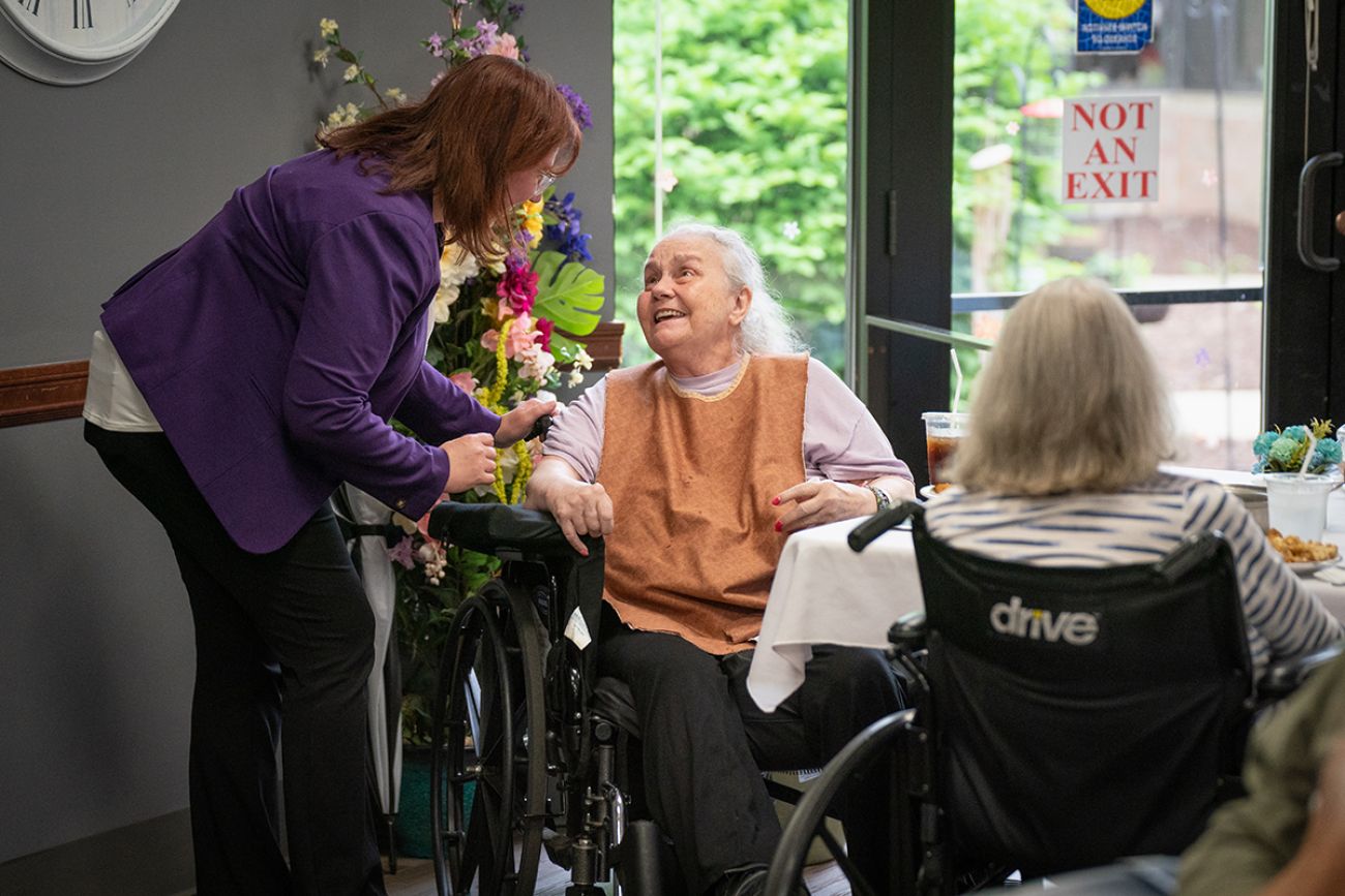 An older woman is talking to a younger woman in a nursing home. 
