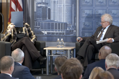 Gov. Gretchen Whitmer covering up her face on stage at the at the Detroit Economic Club. 
